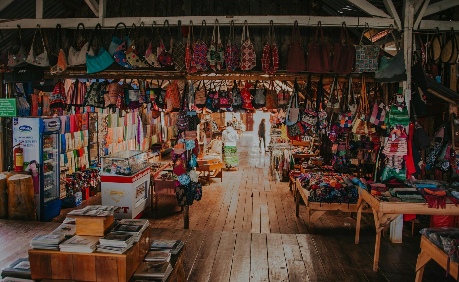 A colorful array of handcrafted bags and textiles in a lively indoor market setting.