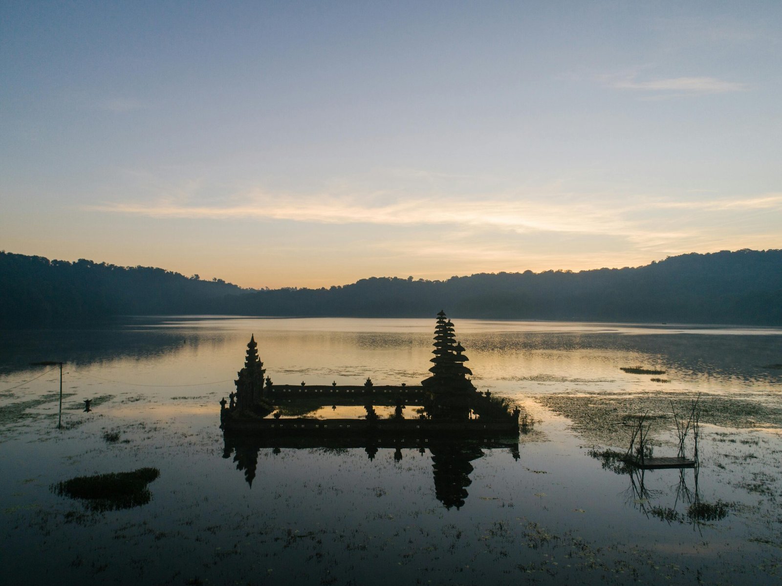 Serene view of Pura Ulun Danu Bratan temple reflecting in Lake Bratan at sunrise.